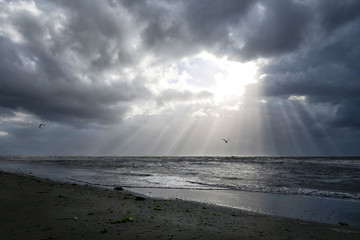 Sonnenstrahlen brechen durch Regenwolken am Strand