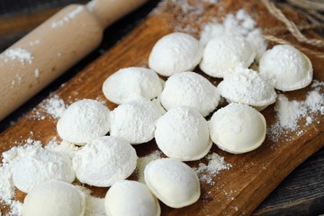 Homemade ravioli and flour on a wooden board 