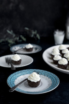 Brownie Bites with Orange Blossom Mascarpone Frosting served with milk.  Photographed on a dark blue background.