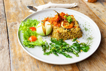 Spicy Fried rice with crispy pork skin with cutlery on wooden table.  thai fusion food.