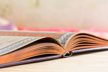Open book with gilded edge on the table, selective focus and shallow depth of field