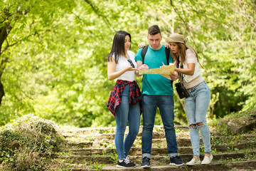 Three friends looking at a map in the forest