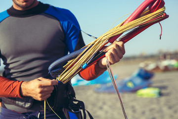 Man sufrers in wetsuits with kite equipment for surfing.