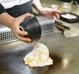 Hand of Chef cooking fried rice on hot pan in front of customers.