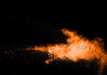 abstract orange dust explosion on  black background. abstract orange powder splatted on black...