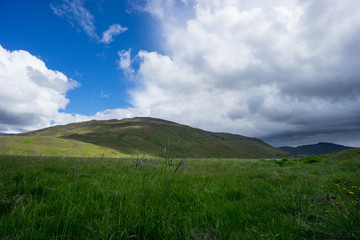 Iceland - Dramatic sky as thunderstorm arrives over endless green mountains and fields