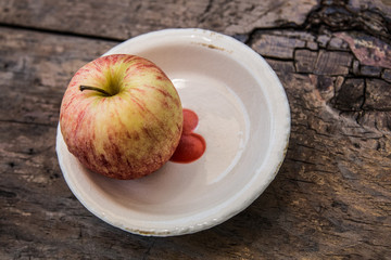 Fresh yellow red apple on ceramic plate with red heart
