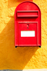 Detailed closeup od red mailbox on yellow wall