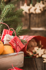 Wooden box with Christmas fruits and gifts, homemade xmas cookies on rustic table. Preparations for holiday