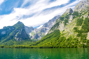 Fototapeta na wymiar Konigssee lake with clear green water, reflection, mountains and sky background, Bavaria, Germany
