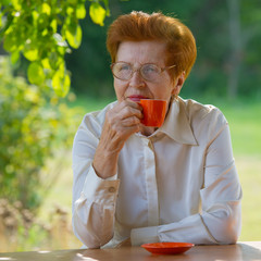 Fototapeta premium smiling woman in glasses is drinking coffee outdoors.