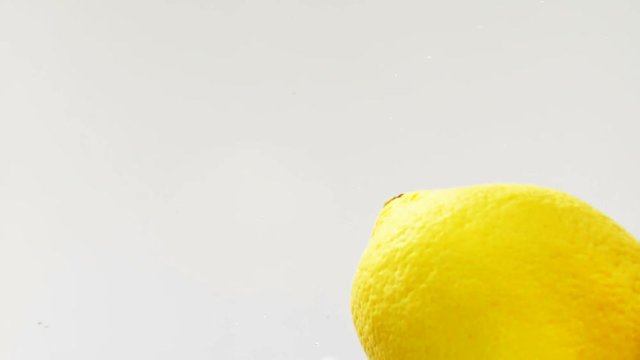 Lemons falling into water in slow motion with a white background