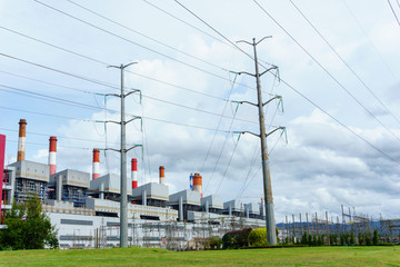 two high voltage electricity pylon and transmission line with power plant background and cloudy blue sky