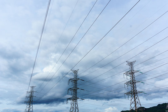 high voltage electricity pylon with cloudy sky at dusk background.
