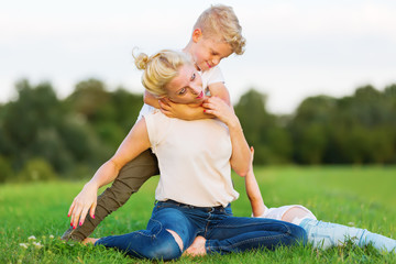 Fototapeta premium woman romps with her son on the grass