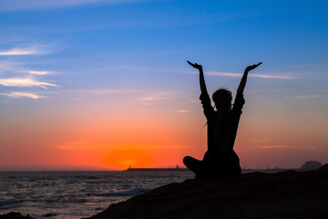 Meditation yoga woman silhouette on the Sea during amazing sunset. Healthy lifestyle.