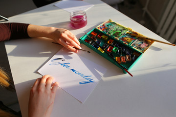 Female calligrapher creates inscription for sale, using brushes 