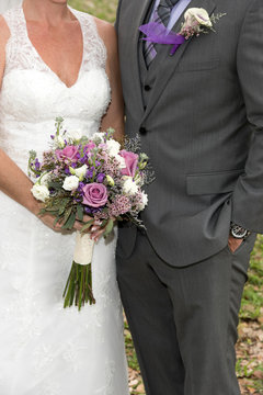 Close up image of bride and groom with bouquet and boutonniere