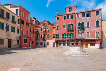 Fototapeta na wymiar Typical square of Venice. Colorful old Venetian houses with green wooden shutters on the windows and stone pavement.