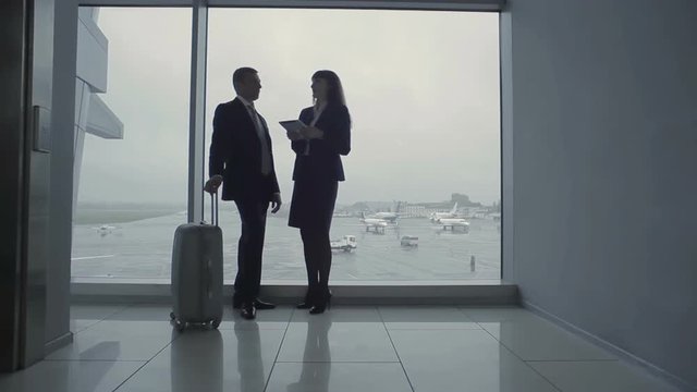 Businessman and airport worker talk near the window