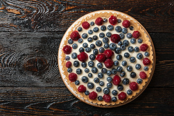 Tartlet cake with raspberries and blueberries on wooden table
