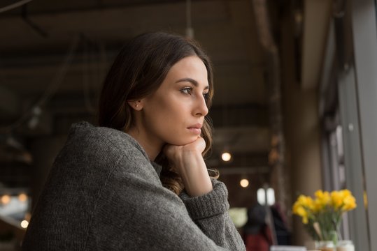 Close up of thoughtful woman with hand on chin in cafe
