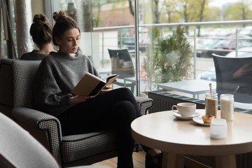 Young woman reading book in cafe