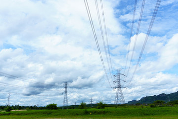 high voltage electricity pylon and transmission line in the field with blue sky and cloud