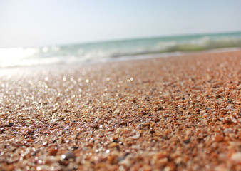 Beach shoreline waves and ocean background with center focus on sand. Colorful summer season scene, holiday theme, vacation background wallpaper. Empty part blur effect template for text advertising