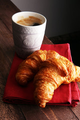 Coffee white cup, croissants on brown wooden background. Breakfa