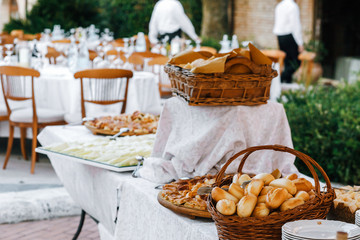 Baskets with different kinds of bread stand on long white table