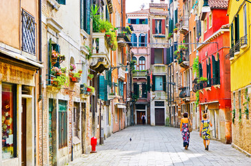 View of the colorful Venetian houses with some visitors walking by in Venice, Italy.
