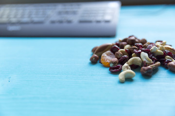 Healthy quick snack in office. Dry fruits and nuts on desk with computer.