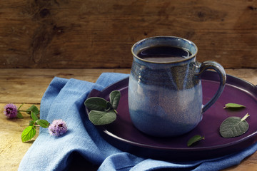 Herbal tea against cold with fresh sage and mint in a blue mug on a rustic wooden table, health care concept, home remedies, flu prevention, copy space, selected focus