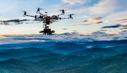 Fototapeta na wymiar The drone with the professional cinema camera flying over the misty mountains at sunset.