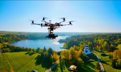 drone with professional cinema camera flying over a autumn park in fall colors under morning light with deep long shadows © Alexey Yuzhakov