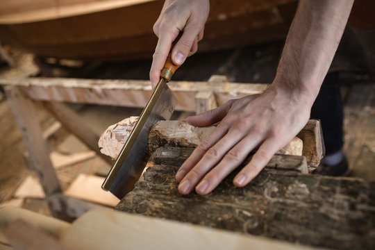 Mid section of carpenter cutting wooden log