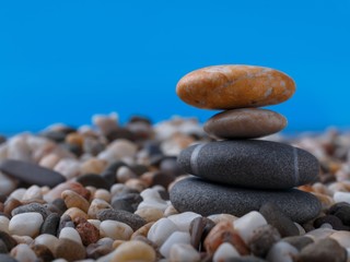 Fototapeta na wymiar Extreme close-up balancing stones on small pebbles. Blue background