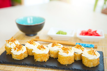 Rolls in a black plate on a wooden table. Fried sushi on black slate surface. Japanese food