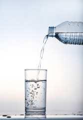 pouring water on a glass on white background,Glass of water, Glass of water isolated on white background,Water pouring from bottle into the glass, isolated on white