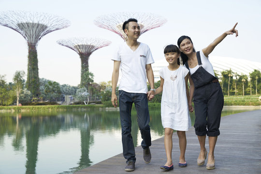 Smiling family of three walking at Gardens by the Bay, Singapore