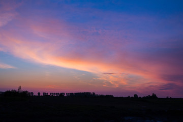 Natural Sunset Sunrise Over Field Or Meadow. Bright Dramatic Sky And Dark Ground. Countryside Landscape Under Scenic Colorful Sky At Sunset Dawn Sunrise. Sun Over Skyline, Horizon. Warm Colours.