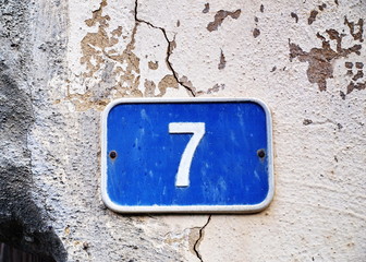 Blue Seven - blaues Schild 7 auf rissiger Wand