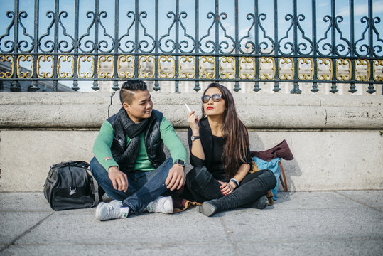 Chinese couple talking , smoking and vaping around Palacio Real in Madrid