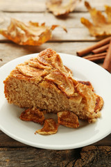 Slice of apple cake in plate on grey wooden table