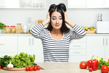 Beautiful young woman with vegetables in the kitchen
