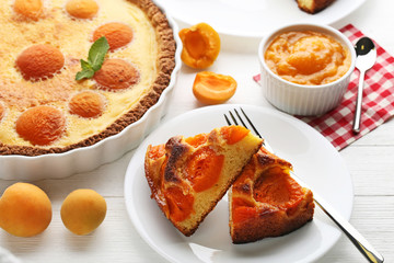 Slices of apricot pie with fruits on white wooden table