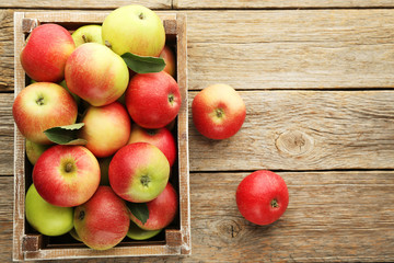 Ripe apples in crate on grey wooden table