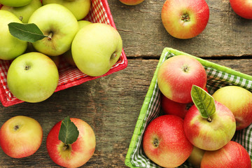 Ripe green and red apples in baskets on wooden table