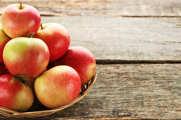 Ripe and sweet apples in basket on wooden table
